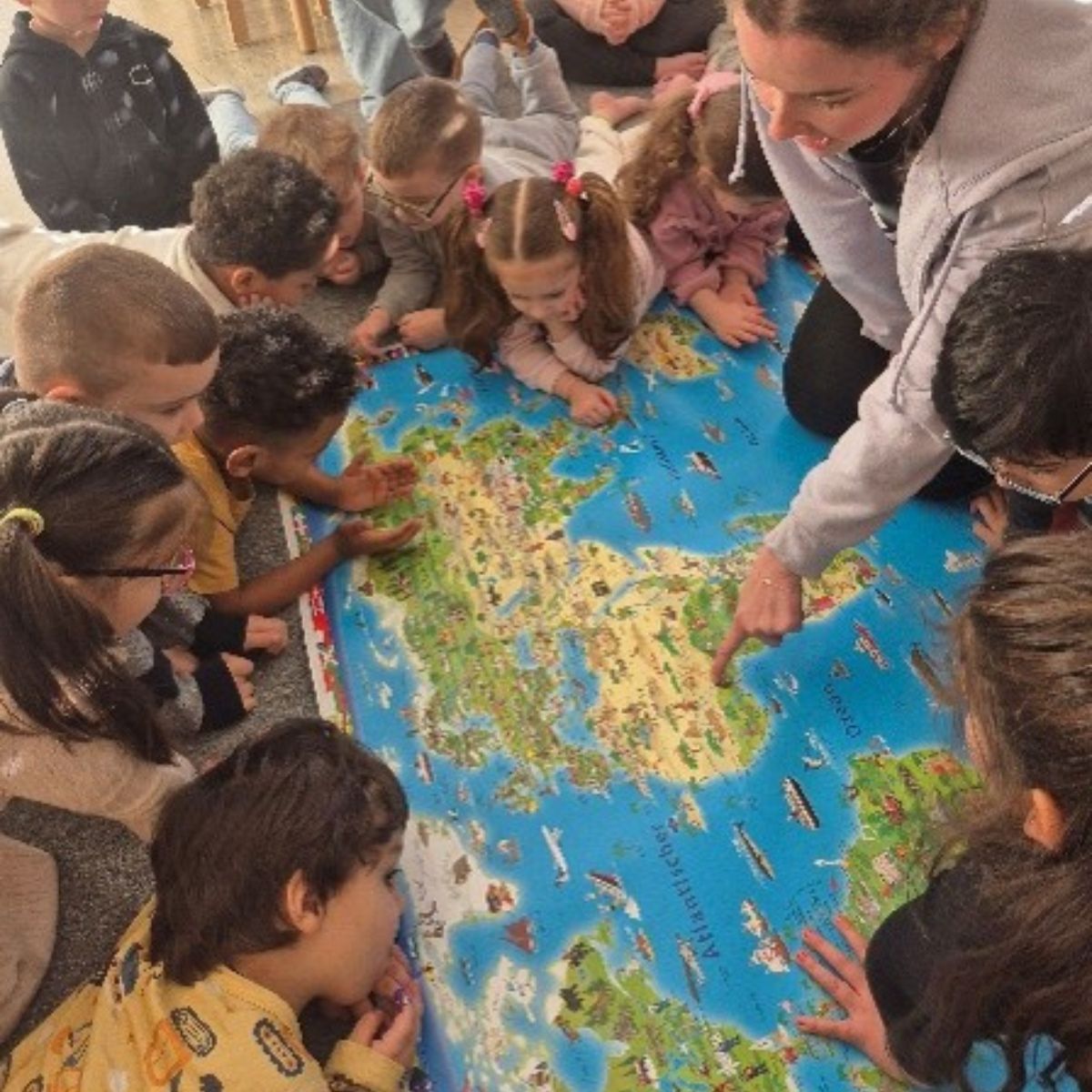 Kinder schauen mit einer erwachsenen Person gemeinsam auf eine Weltkarte